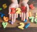 child hands showing a colorful 123 numbers agains wooden table. Concept of Child education, learning mathematics and counting